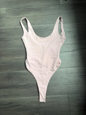 Ljusrosa basic body med tryckknappar - En enkel och stilren ljusrosa body med breda axelband och rundad urringning både fram och bak. Bodyn har tryckknappar i grenen för enkel på- och avklädning. Tillverkad i mjukt stretchigt material som sitter skönt mot kroppen!💓🌸