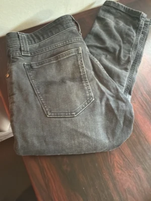 Gråa nudie jeans w28 l34 - Snygga grå jeans i klassisk rak modell med fem fickor och normal midja. Jeansen har en diskret tvättad look och silverfärgad knapp framtill. Perfekta för en avslappnad och trendig stil. Pris kan diskuteras hör av er vid funderingar.