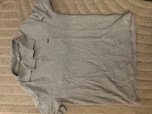Lacoste piké  - Säljer en Lacoste piké tröja står XL men är mer L/M jätte fin grå färg