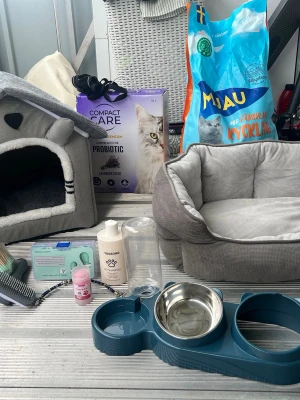 Stort kattpaket med klösträd och tillbehör - Säljer ett komplett kattpaket med stort brunt klösträd, två mjuka kattbäddar, matskål i blå plast och metall, kattlåda med sand, borste, leksaker, kattmat och hygienartiklar. Perfekt för dig som vill ge din katt allt den behöver direkt.