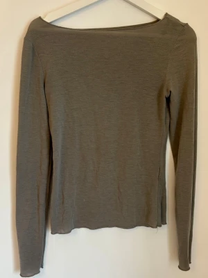 Grön långärmad topp med båtringning - En enkel och stilren grå långärmad topp med båtringad hals. Toppen har en rak passform och är tillverkad i ett mjukt, tunt material som passar perfekt till lager på lager eller för en clean look.