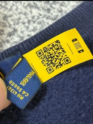 Mörkblå kabelstickad tröja Polo Ralph Lauren - Mörkblå kabelstickad tröja från Polo Ralph Lauren med klassisk röd logga broderad på bröstet. Tröjan har rund halsringning och långa ärmar. Perfekt för dig som gillar stilrena och tidlösa plagg i garderoben.