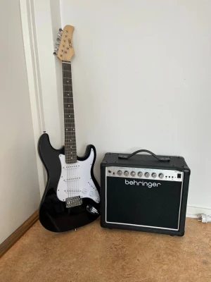 Elgitarr 3rd Avenue med Behringer förstärkare - Säljer en svart elgitarr från 3rd Avenue tillsammans med en Behringer förstärkare. Gitarren har vit plektrumskydd, sex strängar och kromade stämskruvar. Perfekt för dig som vill börja spela elgitarr eller behöver ett extra set till replokalen.  You can only get it via picknick because it’s really hard to package