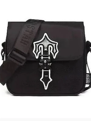 Svart trapstar axelväska med dekorativt spänne - Äkta trapstar axelväska Cool svart axelväska i fyrkantig modell med bred axelrem och ett unikt dekorativt spänne framtill. Väskan har lock och justerbar rem, perfekt för att bära det viktigaste. Materialet ser ut som slitstark textil och detaljerna är i kontrasterande färg.