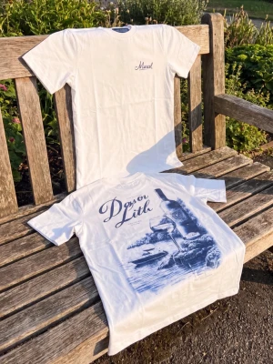 Vit t-shirt med blått tryck - Säljer en vit t-shirt med blått motiv och texten 'Dysor Lith' på framsidan. T-shirten har klassisk passform och rund hals. Perfekt för dig som gillar stilrena plagg med unik print.