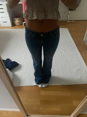 Blå bootcut jeans med låg midja - Säljer ett par blå bootcut jeans med låg midja och klassiska fem fickor. Jeansen har en snygg tvätt och lätt utsvängda ben. Innerbenslängd: 83 cm. Midjemått tvärsöver: 37 cm (stretchig midja)💙💙