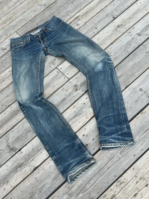 Blå jeans med slitningar - Sitter som en w26 inte w25.       Säljer ett par klassiska blå jeans med snygga slitningar och tvättade detaljer. Jeansen har raka ben och fem fickor, samt kontrastsömmar och fransade benslut. Perfekta för en avslappnad och trendig look.