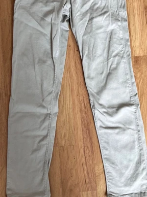 Beige chinos med rak passform - Snygga beige chinos med rak passform och klassisk design. Tillverkade i ett mjukt bomullsmaterial som ger en skön känsla. Perfekta för dig som gillar en clean och enkel stil. Passar till det mesta och är lätta att matcha med olika plagg.