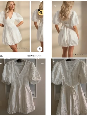 Vit kort klänning med puffärmar - Superfin vit kort klänning med v-ringning och stora puffärmar. Klänningen har markerad midja, knytband i ryggen och ballongformad kjol. Perfekt för dig som vill sticka ut med en trendig och söt look.