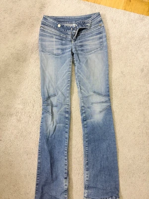 Ljusblå lite bootcut lite strait mittemellan regenerate jeans - Säljer ett par ljusblå bootcut/strait jeans med väldigt kolla detaljer vid knäna och kolla detaljer vid fickorna. Väldigt 2000 still på byxorna. Model ska se lite sliten ut. Tror Jeansen  passar 164 under 