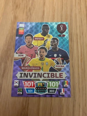 Invincible fotbollssamlarkort - Unikt fotbollssamlarkort med spelarna Son, Mendy, Marquinhos och Pogba. Kortet har färgstark design med texten 'Invincible' och landsflaggor från Sydkorea, Brasilien, Senegal och Frankrike. Perfekt för samlare av fotbollskort.
