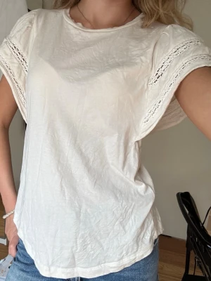 Topp/blus från Lauren - Ralph Lauren  - Söt cremefärgad topp från Lauren - Ralph lauren i mycket bra skick. Använd endast en gång. LACE TRIM JERSEY FLUTTER SLEEVE TOP - T-shirt - bas - mascarpone cream