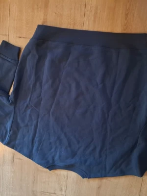 Mörkblå sweatshirt med tryck - Mörkblå sweatshirt med texten 'Oceanside 1994 Los Angeles' i vitt framtill. Tröjan har rund halsringning, långa ärmar och breda muddar vid ärmslut och nederkant. Perfekt för en avslappnad och sportig stil.