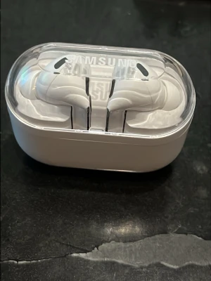 Samsung vita trådlösa in-ear hörlurar - Säljer ett par stilrena vita trådlösa in-ear hörlurar från Samsung. Hörlurarna kommer i ett smidigt laddningsetui med genomskinligt lock och modern design. Perfekta för musik, poddar och samtal på språng.