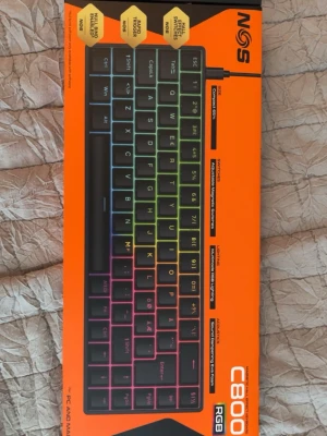 NOS C800 RGB mekaniskt tangentbord - NOS C800 RGB är ett kompakt mekaniskt tangentbord med färgglad RGB-belysning. Tangentbordet har svarta tangenter och en robust design, perfekt för gaming eller skrivbordsbruk. Ansluts med kabel och har anti-ghosting samt mekaniska switchar för snabb respons. Ny pris 2000 ca