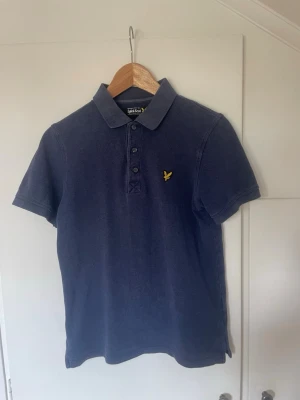 Lyle & Scott Pikétröja - Klassisk mörkblå pikétröja från Lyle & Scott. Storleken på tröjan ska vara S men den sitter mer som XS. Tveka inte på att höra av dig vid minsta fundering!
