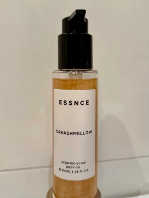 ESSNCE Carashmellow Glow Body Oil - Glow body oil från ESSNCE i doften Carashmellow. Oljan har en skimrande gyllene färg och kommer i en genomskinlig plastflaska med svart pump. Doft av karamell, mjölk och vanilj. Perfekt för att ge huden lyster och en mjuk känsla. Endast testad föll mig inte i smaken.