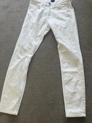 Vita slim jeans med fem fickor - Säljer ett par vita slim jeans med klassisk femficksdesign och smal passform. Jeansen har normal midja och är tillverkade i ett stretchigt material för extra komfort. Perfekta för en clean och fräsch look.