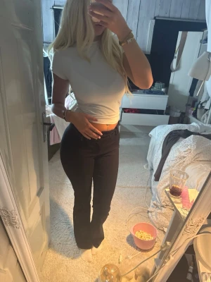 Svarta bootcut kostymbyxor med låg midja  - Säljer ett par svarta kostymbyxor med bootcut-modell och låg midja. Byxorna har en smickrande passform och är perfekta för dig som gillar en klassisk men trendig look. Materialet ser ut att vara bomull eller en bomullsblandning.