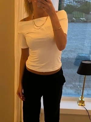 Vit offshoulder topp - Trendig vit topp med offshoulder-design och korta ärmar. Toppens passform är tight och den är något croppad