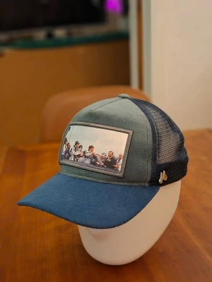 Limited edition maggiore keps - Snygg velvet keps i grönt och blått med mesh på sidorna och bak. Framtill finns ett tryck med ett foto av ett gäng personer. Kepsen har böjd skärm och en liten metallogo på sidan. Perfekt för en avslappnad stil