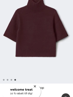 Vinröd stickad polotröja kort ärm - Mysig vinröd stickad polotröja med korta ärmar och ribbade detaljer vid hals, ärmslut och nederkant. Perfekt till jeans eller kjol för en trendig look. Materialet ser ut att vara mjukt och värmande.