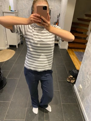 Gråvit randig kortärmad topp - Säljer en stilren kortärmad topp med grå och vita horisontella ränder. Toppen har en klassisk rund halsringning och är i en mjuk, bekväm bomullsblandning. Perfekt för dig som gillar enkel och fräsch stil.