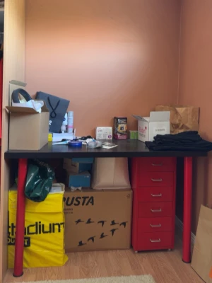 Skrivbord med röda metallben och lådor - Snyggt skrivbord med svart bordsskiva och fyra röda metallben. Ena sidan har en röd metall hurts med fem lådor och silverfärgade handtag. Perfekt för plugget eller hemmakontoret, ger en cool industriell vibe till rummet.