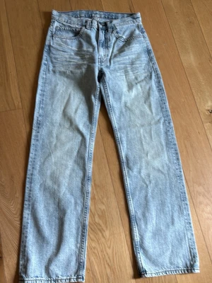 Ljusblå raka jeans Cheap Monday - Säljer ett par ljusblå raka jeans från Cheap Monday med klassisk femficksmodell och coolt tryck på bakfickan. Jeansen har hög midja och är tillverkade i denim med tvättad look. Perfekta för en avslappnad streetstil.