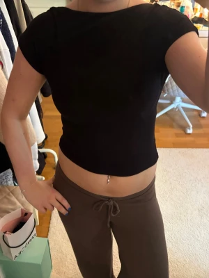 Svart croppad topp med öppen rygg - Säljer en svart croppad topp med korta ärmar och en riktigt snygg öppen rygg. Perfekt för dig som vill ha en enkel men ändå statement topp till din outfit. Materialet känns mjukt och stretchigt, troligen bomull eller polyester. Skriv pm vid funderingar!☺️