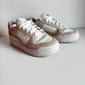 Adidas Forum Bold sneakers i beige, storlek 39 1/3 - Snygga adidas Forum Bold IG0270 i färgen Alumina / Sand Strata / Cloud White.  * Storlek: EU 39 1/3 * Modell: adidas Forum Bold * Artikelnummer: IG0270 * Färg: off-white/beige * Tillverkade i Indonesien * Produktionsdatum: 08/2022  Mycket fint begagnat skick. Normalt bruksslitage och lite lätt smuts på mockan, men inga större skador. Sulorna är i fint skick.