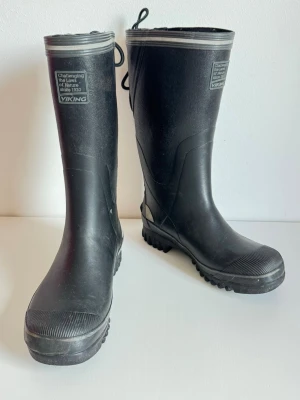 Viking gummistövlar stövlar – vintage, retro strl 37 - Viking gummistövlar – vintage, strl 37  Snygga och klassiska svarta Viking gummistövlar i storlek 37.  Äldre modell som bedöms vara från ca 1990-talet, med den karaktäristiska äldre Viking-designen, silverfärgade detaljer och snörning upptill.  Gott begagnat skick med normala bruksspår. Gummit är helt och utan sprickor. Även fodret är helt och funktionellt, med viss normal ålders- och användningspåverkan.  Kraftig profilerad yttersula med bra grepp. Viking-logotyp både framtill och baktill.  Mär