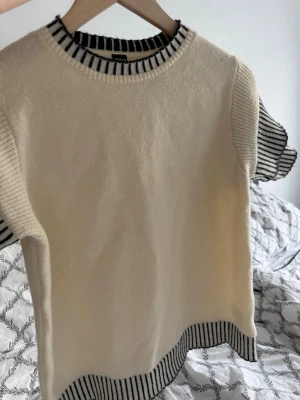 Stickad topp från SHEIN med ränder - Krämvit stickad topp från shein med svarta och vita ränder på krage, ärmslut och nederkant. Kortärmad modell