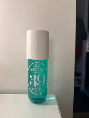 Sol de Janeiro Cheirosa 39 Parfymmist - Fräsch parfymmist från Sol de Janeiro, Cheirosa 39. Flaskan är turkos med vit text och har en rundad form samt vit spraykork och lock. Perfekt för dig som gillar tropiska och fräscha dofter. Flaskan är genomskinlig och modern i designen.