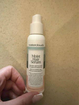 Waterclouds Moist Hair Serum - Moist Hair Serum från Waterclouds för torrt och sprött hår. Innehåller glycerin och natriumhyaluronat för att återfukta och stärka håret. Kommer i en vit plastflaska med pump och stilren design.