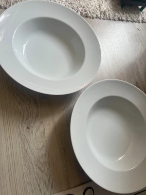 Två vita djupa tallrikar - Säljer två vita djupa tallrikar i porslin, perfekta för soppa, pasta eller sallad. Två glitter glas och två övriga glas ”vaser”, allt för 100kr 