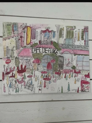 Handgjord Färgglad tavla Café de Flore - Unik tavla med motiv av Café de Flore i Paris. Illustration i lekfull stil med många färger som rosa, rött, grönt och blått. Motivet visar ett livligt kaféliv med många små figurer, parasoller och detaljerade byggnader. Perfekt som dekoration för dig som gillar konst och Paris.