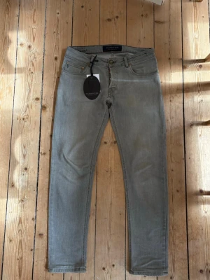 HANDPICKED JEANS - ORVIETO - Säljer dessa handpicked jeans i modell ”Orvieto”, slim fit. Väldigt snygg grå tvätt och bra skick. Storlek 32. Minimal slitning precis under gylfen. Jeansen är uppsydda hos skräddare för att passa 185-190cm. Orginaltagg medföljer. Nypris 2000. Hör av dig vid frågor! 