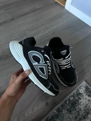 Dior b30s vit svart - Snygga svarta Dior sneakers med vita detaljer och vita skosnören. Skorna har en chunky sula i vitt och ovandel i mesh och läder. Perfekta för dig som vill ha en trendig och exklusiv look till vardags. Klassisk low-top modell.