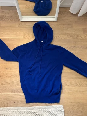Kornblå cashmere hoodie - En stilren kornblå hoodie. Hoodien har långa ärmar och ribbade muddar vid ärmslut och nederkant. Tillverkad i cashmere som känns skönt mot huden. Perfekt för en avslappnad look. Jag är 161 cm lång.