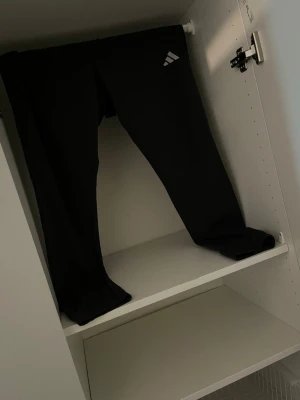 Svart hoodie med dragsko och en helt nytt adidas’s byxa   - Säljer en svart hoodie med klassisk huva och dragsko. Hoodien har en enkel design med en liten vit logga på bröstet. Perfekt för chill dagar eller när du vill ha en clean look. Mjuk och skön bomullskänsla.