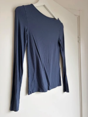 Mörkblå långärmad topp - En enkel och stilren mörkblå långärmad topp med rund hals. Tillverkad i mjukt material som känns skönt mot huden. Perfekt att matcha med jeans eller kjol för en clean look.