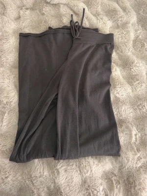 Mörkgrå omlottbyxa med knytband - Mörkgrå omlottbyxa i mjukt och stretchigt tyg. Byxan har ett brett knytband i midjan och en avslappnad passform med raka ben. Perfekt för en chill och stilren look.