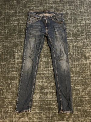 Nudie Jeans Lean Dean - Säljer ett par blå slim fit jeans med fransad kant nedtill. Jeansen har klassisk femficksdesign, kontrastsömmar och normal midja. Perfekta för dig som gillar en enkel men snygg look. Jeansen är i storlek W31 och L36
