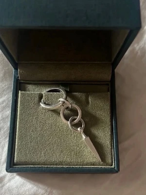 Silvrigt örhänge med kedjedetalj - Coolt örhänge i silver från Maria Nilsdotter. Modern och edgy design som passar dig som gillar unika accessoarer. Perfekt för att lyfta din stil med en statement piece.