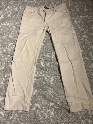 Beiga linnebyxor från Dressmann - Snygga beiga linnebyxor från Dressmann i rak modell. Byxorna har klassisk femficksdesign och är tillverkade i ett lätt och luftigt linnematerial, perfekta för en avslappnad och stilren look.