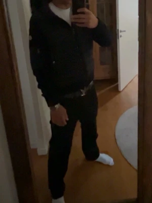 Svart pufferjacka från Moncler - Säljer en svart pufferjacka från Moncler  med huva och dragkedja framtill. Jackan har ribbade muddar, två fickor med knappar och en extra ficka på ärmen. Klassisk Moncler -logga på armen och stilren design som passar perfekt till vintern. Erbjud ditt pris!!