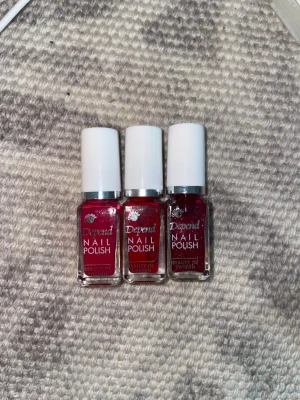 Tre röda nagellack från Depend - Säljer tre snygga nagellack från Depend i olika röda nyanser. Två av lacken har en klassisk röd färg medan det tredje har glittereffekt. Alla kommer i små, fyrkantiga glasflaskor med vita lock. Perfekt för dig som vill ha variation på naglarna!