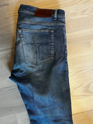 tiger of sweden jeans  - Pris går o diskuteras fraktas inom 8 h Snygga mörkblå jeans med klassisk femficksdesign och en brun läderpatch i midjan. Jeansen har raka ben och subtila slitningar för en avslappnad look. Perfekta till en streetwear-outfit eller till vardags. Materialet är robust denim i bomull.