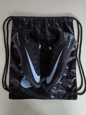 Nike Mercurial Vapor 16 elite - Snygga svarta Nike Air Zoom vapor 16 elites med ljus blå swoosh på sidan och textdetaljer. Skorna har snörning och dobbar för bra grepp på planen. Skorna är andvända ett fåtal gånger och är i mycket bra skick vid frågor och funderingar är det bara att höra av sig.                       Mvh Atle